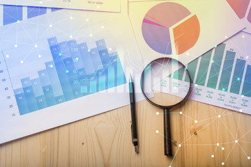 Magnifying glass and documents with analytics data lying on table,selective focus