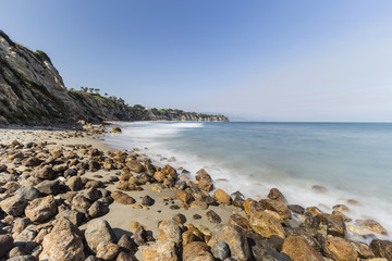 Rocky shore with motion blur waves at secluded Dume Cove in Malibu, California.