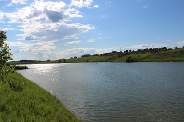 The lake is in good sunny weather. The water is riddled with a slight ripple. The shores of the lake are covered with luscious green vegetation.