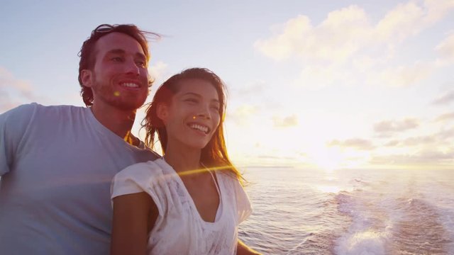 Romantic couple enjoying sunset over the ocean on cruise ship sailing on open sea. Woman and man in love on boat travel sailing during vacation. RED EPIC.