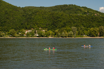 Fototapeta na wymiar canoing on river in summer across hills. water canoing on river happy sport