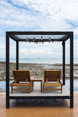 Two wooden chairs on rock beach in Chonburi, Thailand