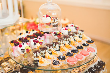 Delicious and tasty dessert table with cupcakes shots at reception closeup