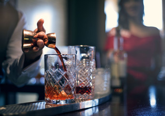 bartender poring drink with lady in backgroun