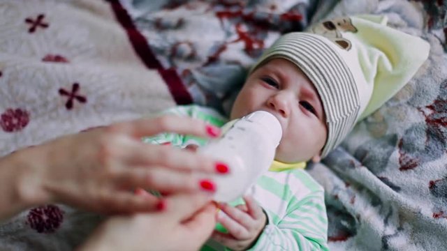 A newborn baby drinks from a bottle