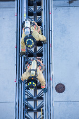 Firefighter training entering and exiting a building on a truck ladder overhead view