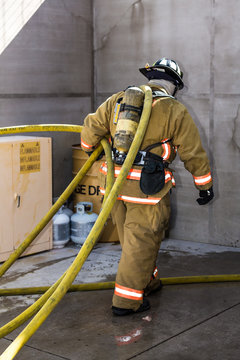 Firefighter Training Entering A Building With A Charged Hose