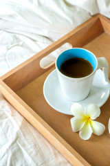coffee cup in wood tray on the bed background in the morning time.
