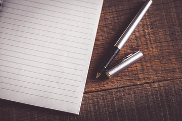 pen and book on wood background with filter effect retro vintage style