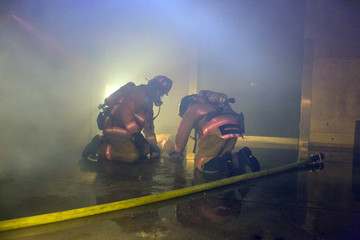 Firefighter training exiting the building with a victim