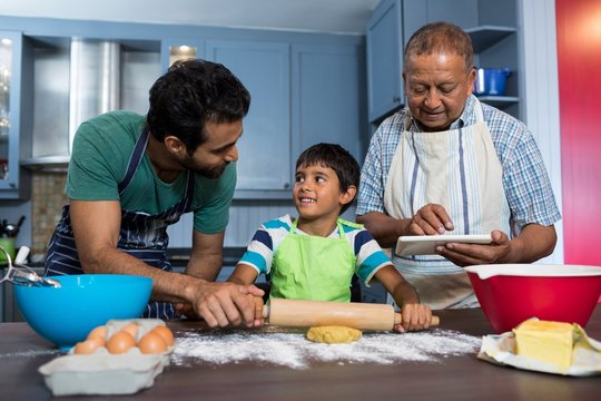 Man using table while standing by father and son preparing food