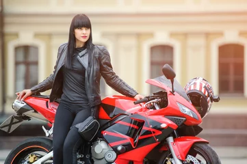 Foto op Plexiglas Freedom and style. Colorful portrait of a young woman with a red motorcycle. © lanarusfoto
