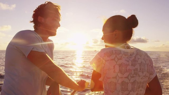 Cruise ship - Romantic couple enjoying sunset over the ocean on small cruise ship sailing open sea. Woman and man in love on boat travel sailing during vacation. RED EPIC.
