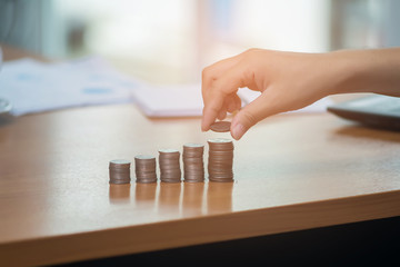 Hand stacking coins saving on desk workplace.