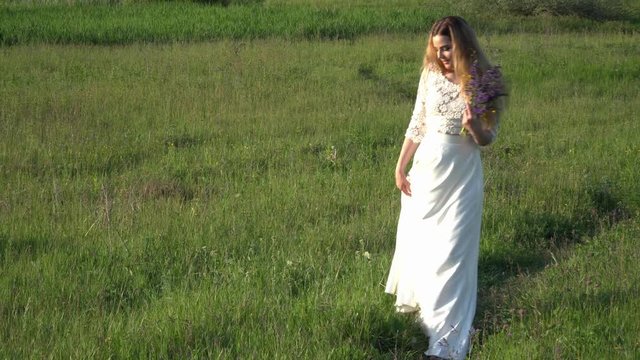 Beautiful young woman walking on the meadow with flowers