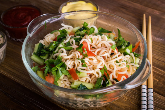 Noodles with vegetables on a wooden background