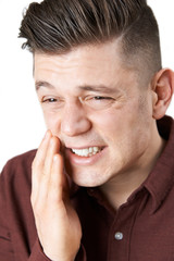Studio Shot Of Young Man Suffering With Toothache