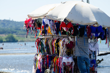 Summer. Peddler sells bathing suits for woman at the beach with a cart