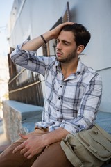 Man with eyes closed sitting on retaining wall