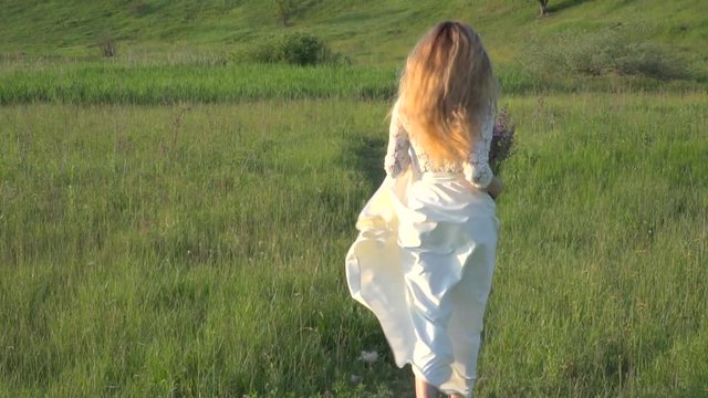 Beautiful blonde woman in white dress running on the meadow slow motion