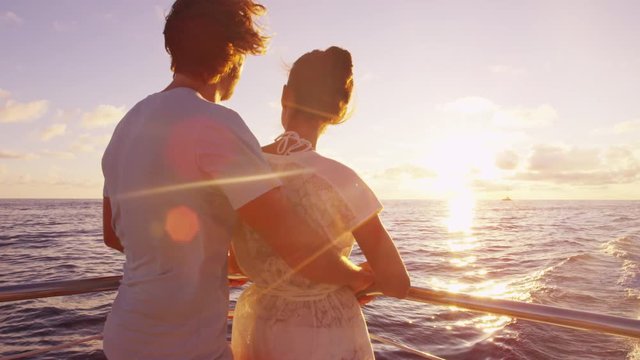 Cruise ship - Romantic couple enjoying sunset over the ocean on small cruise ship sailing on open sea. Woman and man in love on boat travel sailing during vacation. RED EPIC.