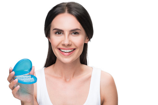 Happy girl holding transparent plastic teeth for orthodontic correction