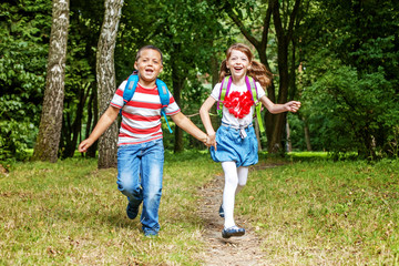Fototapeta premium Children hold hands. Students running in the park. The concept is back to school.