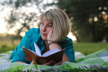 woman in park with book on the grass