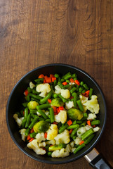Mixed vegetables in a frying pan. on wood table with copy space. top view