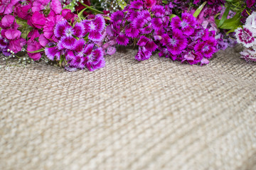 Bright purple and violet flowers on a burlap background, top horizontal boards, copyspace