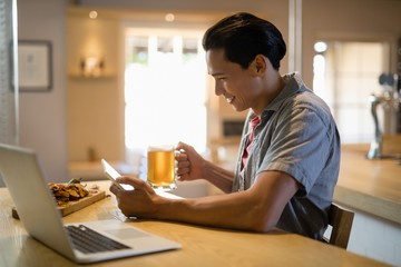 Fototapeta premium Man using digital tablet while having beer in restaurant