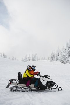 Couple riding snowmobile in snowy alps
