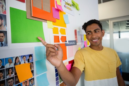 Smiling man pointing at sticky notes in office