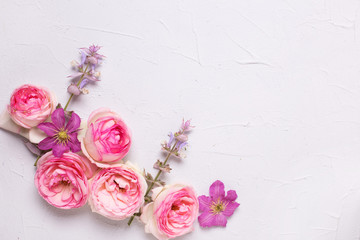Fototapeta na wymiar Pink roses and violet summer clematis flowers on grey textured background.