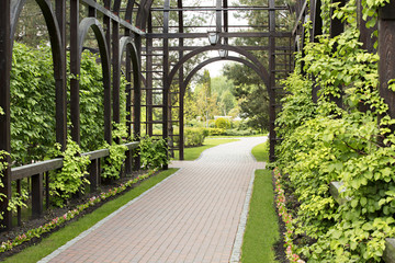 A high quality wooden gazebo surrounded by a beautiful bush, a well-groomed lawn and flowers