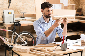Concentrated lumber craftsman working with raw material in workshop