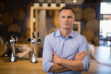 Obraz premium Man standing with arms crossed near bar counter