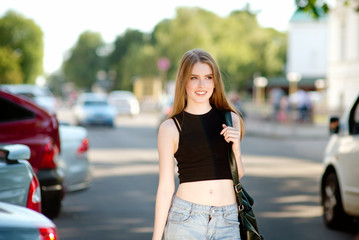 A beautiful young stylishly dressed girl walks in the city, drinks juice or a cocktail, eats sweets, makes selfie on a mobile phone