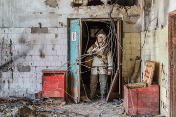 A man in uniform in the corridor of a dilapidated building among wires