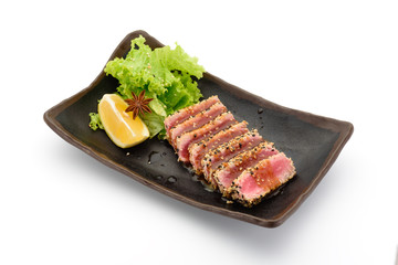 Tataki (tuna fillet) on a black plate isolated on white background,