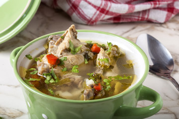 Homemade chicken soup in a green bowl with spoon