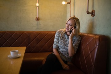 Obraz premium Beautiful woman talking on mobile phone in restaurant