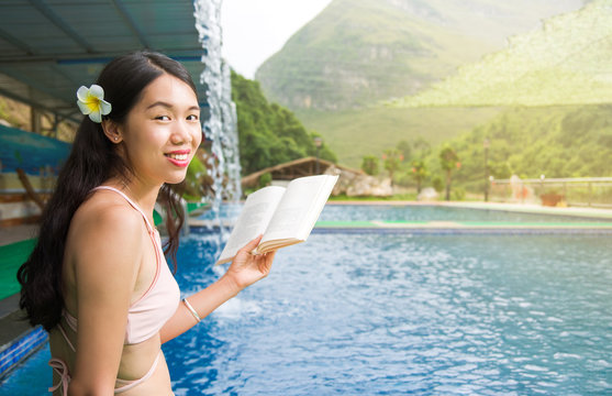 Girl in bikini reading a book by the pool - Powered by Adobe