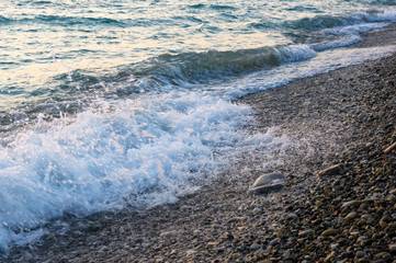 Obraz premium sea pebble beach with multicoloured stones, waves with foam