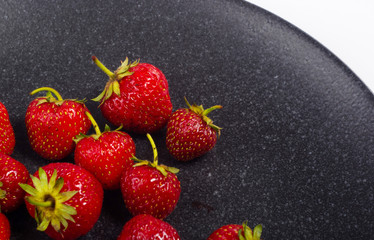fresh ripe strawberries on black ceramic plate