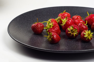 fresh ripe strawberries on black ceramic plate