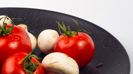 fresh tomatoes and mushrooms - champignons on black plate