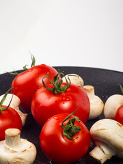 fresh tomatoes and mushrooms - champignons on black plate
