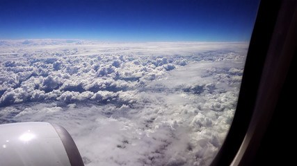 Flying over the clouds. View from plane aircraft passenger window. Clouds and skyline horizon panoramic view.