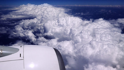 Flying over the clouds. View from plane aircraft passenger window. Clouds and skyline horizon panoramic view.